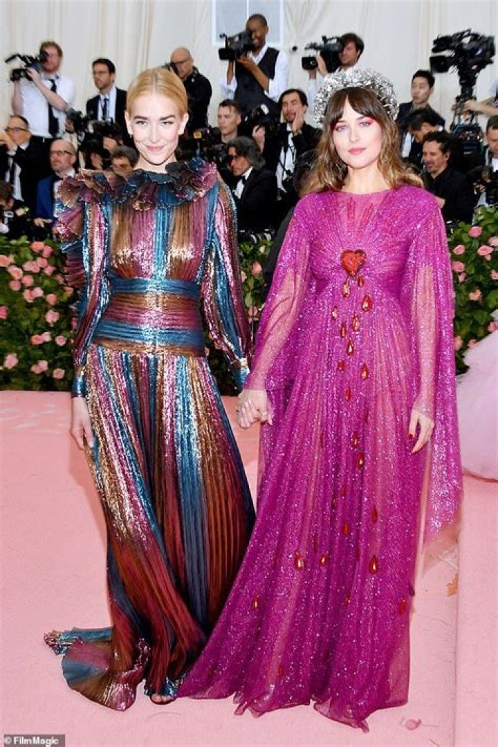 Dakota Johnson, 29, holds hands with younger sister Grace, 19, as they
